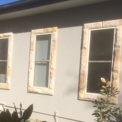 Rock faced sandstone cladding to the window's edging   
